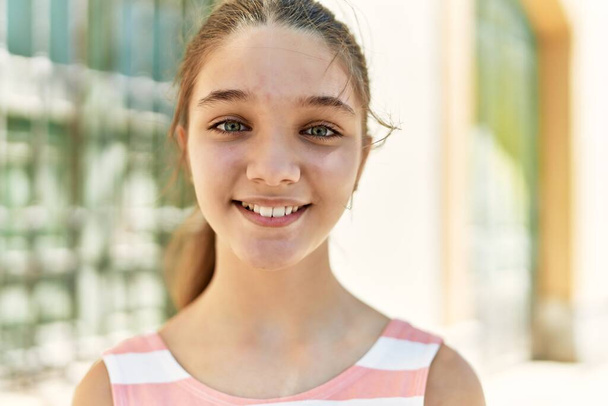 Кавказская девочка-подросток улыбается счастливо стоя в городе. - Фото, изображение