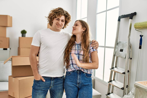 Молода біла пара посміхається впевнено обіймає один одного в новому будинку
 - Фото, зображення