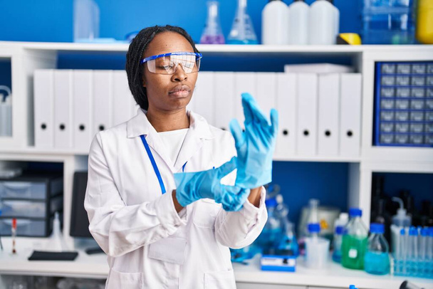 Mujer afroamericana vistiendo uniforme científico y guantes laboratorio - Foto, imagen