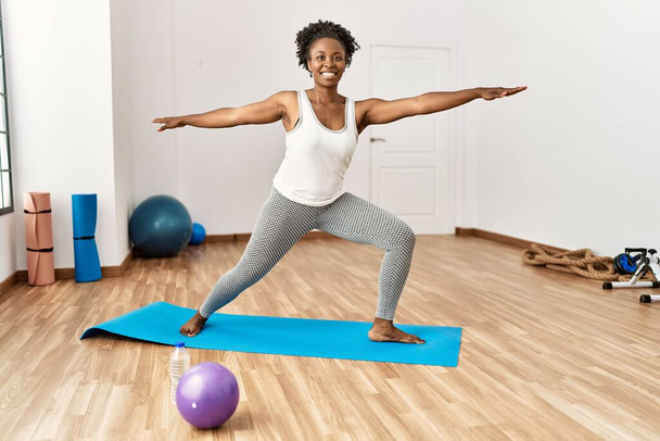 Африканская американка улыбается уверенной тренировкой йоги в спорткомплексе - Фото, изображение