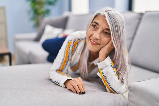 Middle age grey-haired woman smiling confident lying on sofa at home - Foto, Imagen