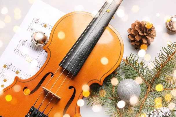 Violin with Christmas decor and music note sheets on light background - Fotó, kép