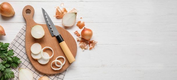 Composition with fresh onion, cutting board and knife on white wooden background with space for text, top view - Фото, изображение