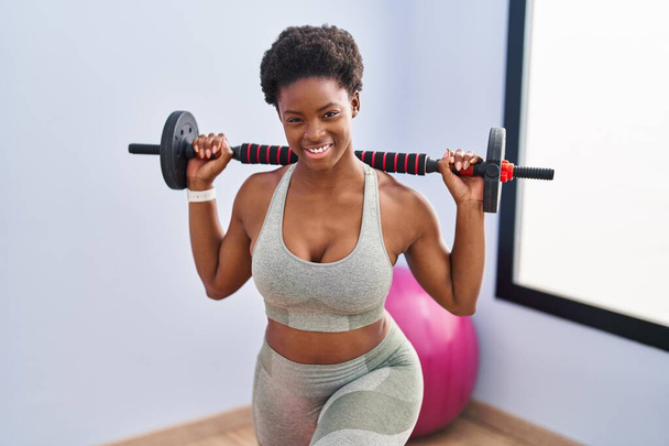 Afro-americana mujer sonriendo confiado entrenamiento piernas exersice en sport center - Foto, Imagen