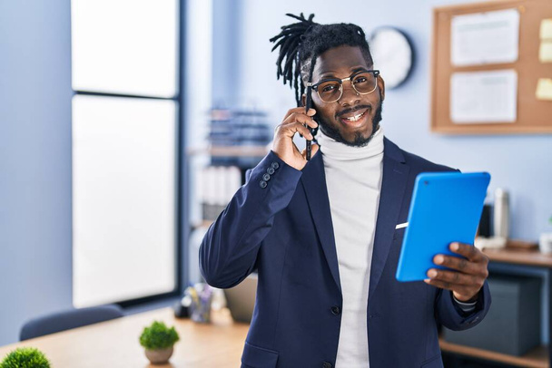 Африканська американська бізнес-працівниця за допомогою тачпада і розмови на смартфоні в офісі - Фото, зображення
