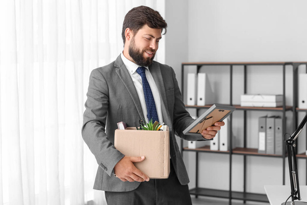 Fired young man holding box with his stuff in office - Foto, Bild