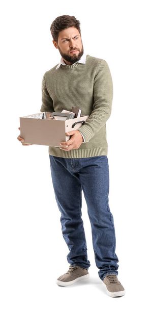 trieste ontslagen jonge man holding box met persoonlijke spullen op witte achtergrond - Foto, afbeelding