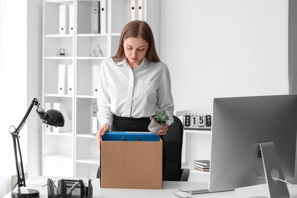 Fired young woman packing her personal stuff in office - Foto, afbeelding