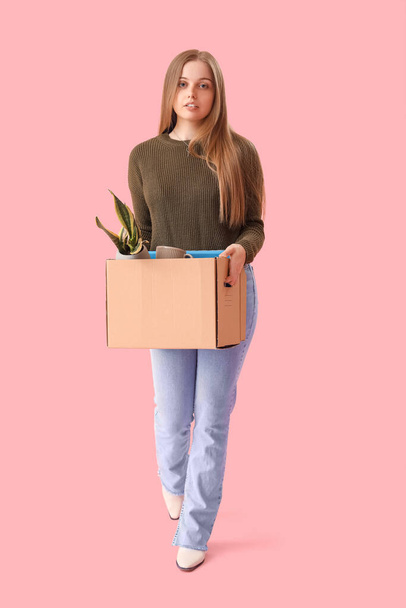 Gebrannte junge Frau hält Schachtel mit persönlichen Sachen auf rosa Hintergrund - Foto, Bild