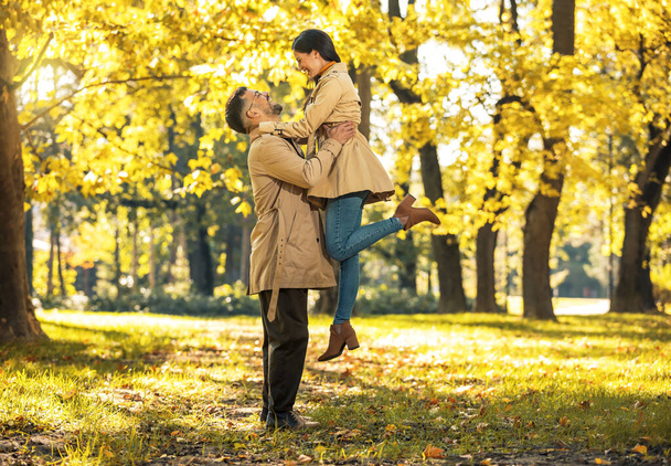 Закохана пара обіймає осінній парк, насолоджуючись прекрасним осіннім днем
. - Фото, зображення
