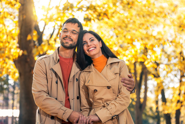 Para zakochanych spacerujących po jesiennym parku, cieszących się pięknym jesiennym dniem. - Zdjęcie, obraz