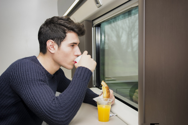 Rafraîchissements jeune homme manger dans un train - Photo, image