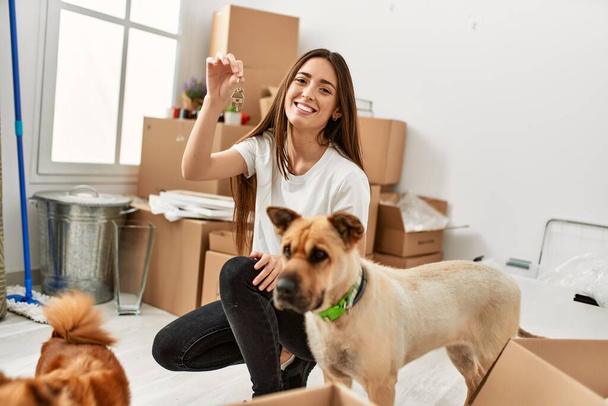 Young hispanic woman smiling confident holding key of new house at new home - Foto, Imagen