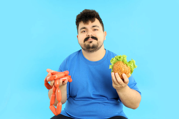 Concept of weight problems, young fat man on blue background - Foto, imagen
