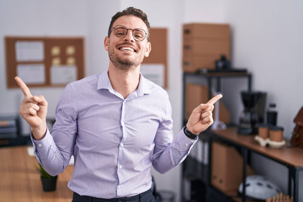 Молодий іспаномовний чоловік в офісі посміхається впевнено вказуючи пальцями на різні напрямки. копіювання простору для реклами
  - Фото, зображення