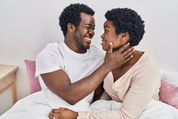 afro americano uomo e donna coppia abbracciare ogni altro seduta su letto a camera da letto - Foto, immagini