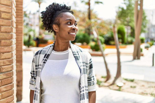 若いアフリカ系アメリカ人の女の子が笑顔で街に立って. - 写真・画像