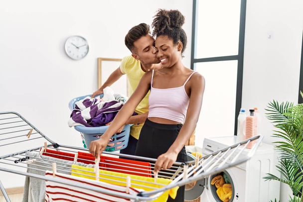 Man and woman couple kissing and hanging clothes on clothesline at laundry room - Photo, Image