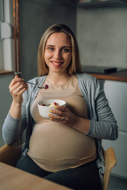 young adult caucasian pregnant female eats fruit at home - Valokuva, kuva