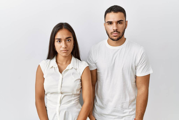 Young interracial couple standing together in love over isolated background relaxed with serious expression on face. simple and natural looking at the camera.  - Photo, Image