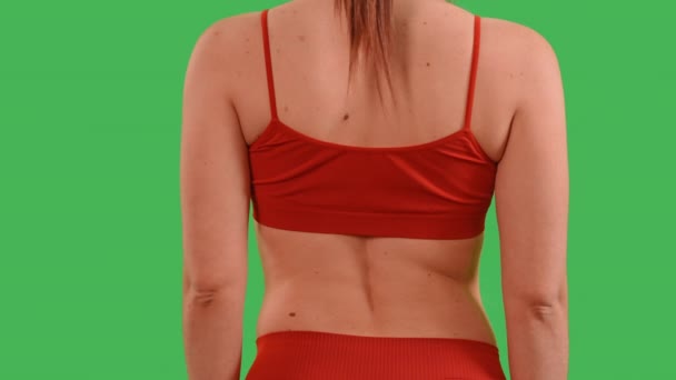 mujer vestida top rojo y polainas deportivas tocan el dolor de espalda después del entrenamiento concepto de cuidado de la salud Aislado en el estudio de pantalla verde - Metraje, vídeo
