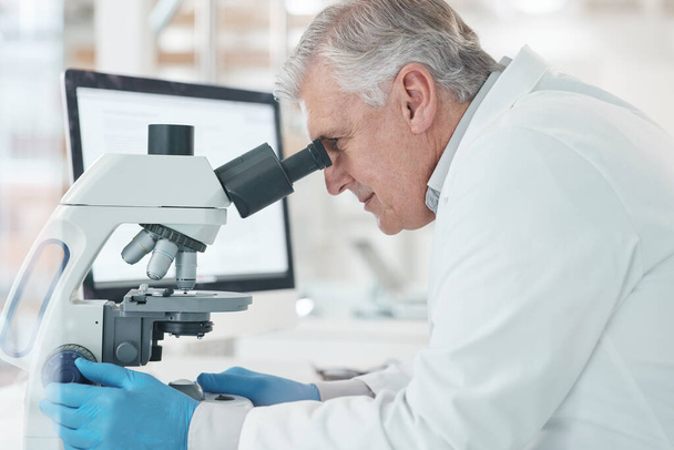 Trabajando hacia la cura precisa. un científico maduro usando un microscopio en un laboratorio - Foto, imagen