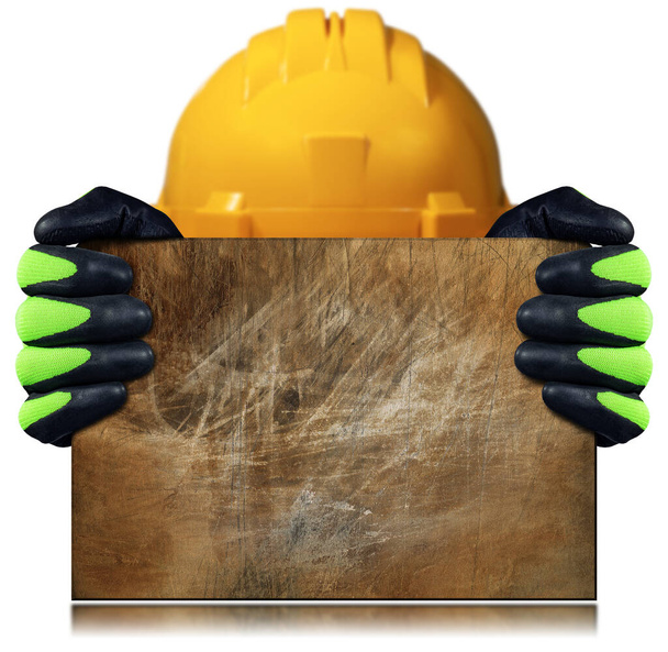 Manual worker with protective work gloves and yellow hardhat holding a rusty metal plate or metal sheet, isolated on white background with copy space. - Photo, Image