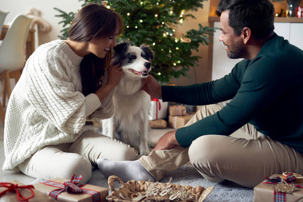 Multi ethnicity couple spending time with dog at Christmas - Φωτογραφία, εικόνα