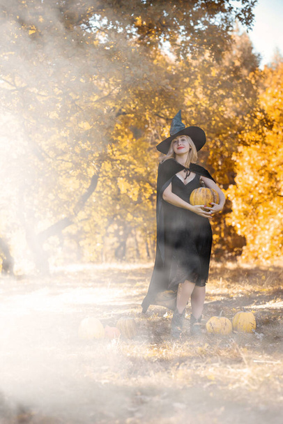 Мистическая сцена с ведьмой в черной шляпе и платье, плащ, стиль на Хэллоуин, дамы модный карнавал традиционный костюм - Фото, изображение