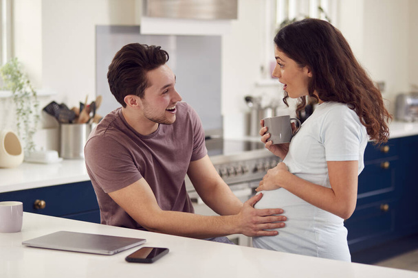 Izgatott terhes transznemű pár otthon a konyhában együtt férfi megható nő gyomra - Fotó, kép