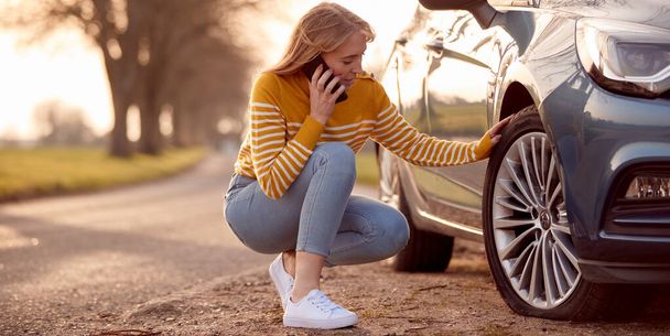 Woman Calling For Help On Phone After Car Breakdown On Country Road With Tyre Puncture - Valokuva, kuva
