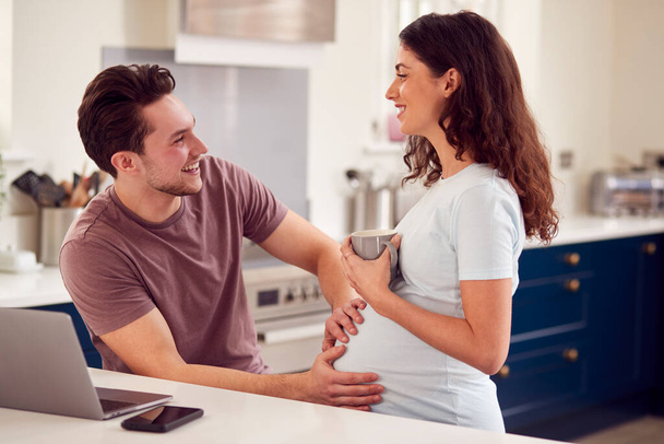 Excited Pregnant Transgender Couple At Home In Kitchen Together With Man Touching Woman's Stomach - Foto, imagen