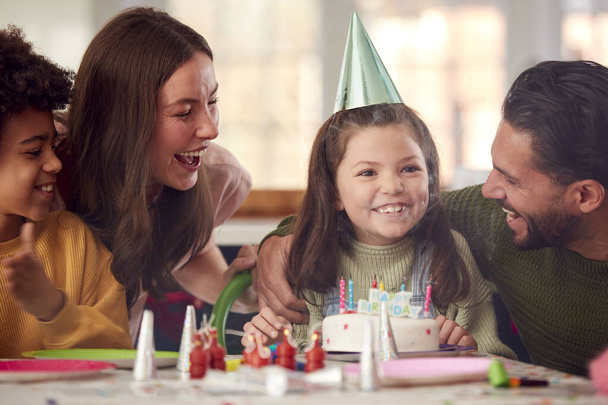 Girl Blowing Out Candles On Birthday Cake At Party With Parents And Friends At Home - Фото, изображение