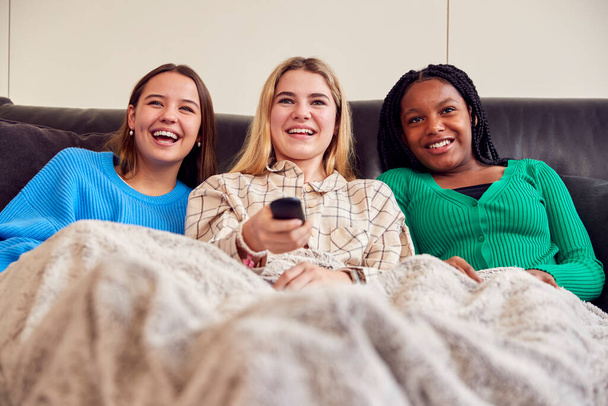 Group Of Multi-Cultural Teenage Girl Friends Snuggled Under Blanket Watching TV At Home - Zdjęcie, obraz