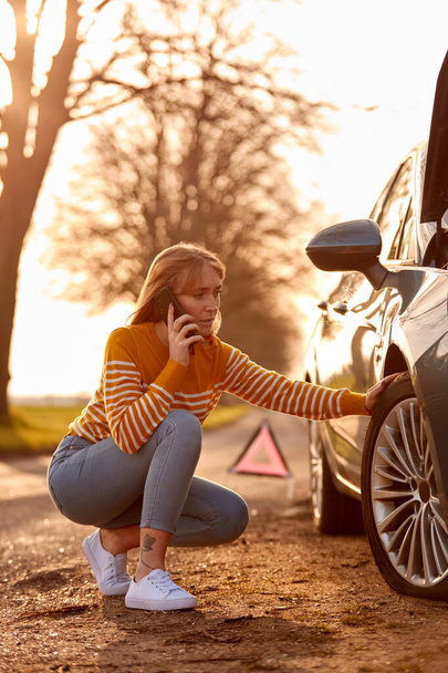 Woman Calling For Help On Phone After Car Breakdown On Country Road With Tyre Puncture - Foto, immagini