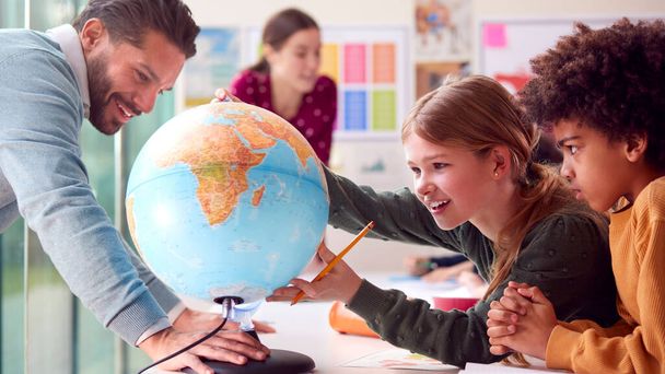 Group Of Multi-Cultural Students With Teachers In Classroom Looking At Globe In Geography Lesson - Foto, Imagem
