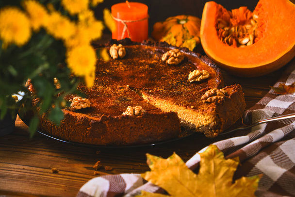 Traditioneller Kürbiskuchen mit Walnüssen und Zutaten zum Kochen auf einem Holztisch. Herbstliches Essen im dunklen Stil - Foto, Bild