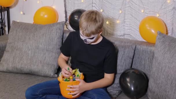 A criança tira os doces do balde para o Halloween. O menino celebra Truque ou Doce. - Filmagem, Vídeo