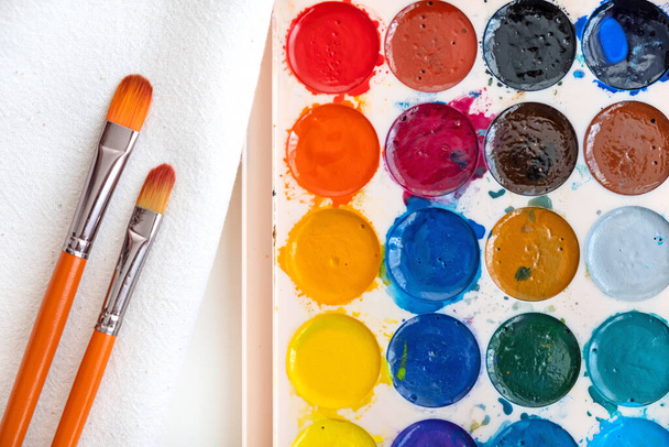 Box of used watercolor palette and paintbrushes. - Valokuva, kuva