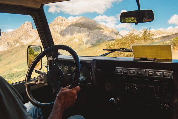 hands of unrecognizable people, holding a steering wheel, driving along a mountain road in an all-terrain car. travel and adventure. Active turism. - 写真・画像