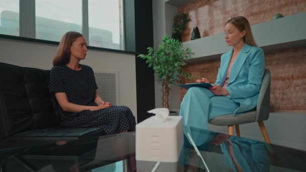 brunetka žena sedí na gauči vyprávět psychoterapeut o svém životě během terapie terapeut psaní poznámek držící desky - Záběry, video