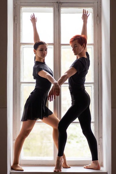 Két kaukázusi táncos lép fel az ablakon. Gyönyörű fiatal balett táncosok - Fotó, kép