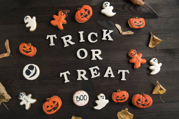 Halloween maquettes blanc et orange délicieux biscuits au gingembre est situé sur une surface en bois brun. Inscription : astuce ou régal. - Photo, image