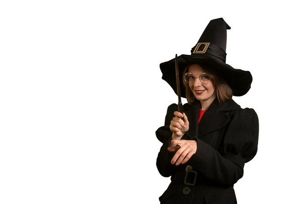 Γυναίκα σε μορφή μάγισσα χαμογελά μυστηριωδώς και κρατά μαγικό ραβδί στα χέρια σε λευκό φόντο. Μάγισσα κοστουμιών. Μεμονωμένα. - Φωτογραφία, εικόνα