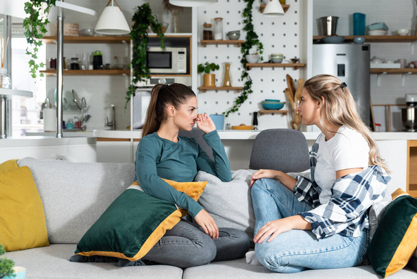 Young women lesbian couple LGBTQ+ roommates having argue due the infidelity and cheating. Two girls in relationship having difficulty caused by jealousy. Marriage problems concept. - 写真・画像