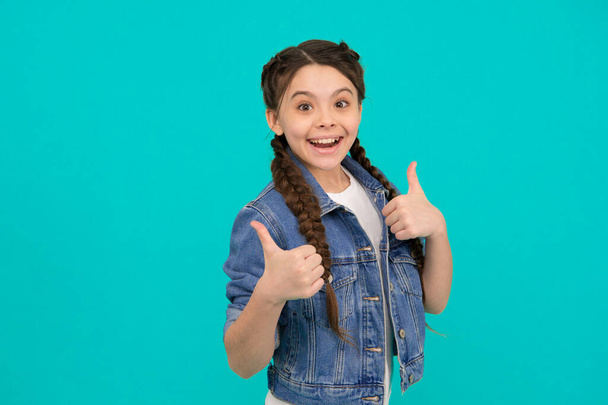 Beauty at its best. Happy child give thumbs up blue background. Little girl smile gesturing thumbs up. Hair salon. Haircare cosmetic products. Approval gesture. Hand sign. She deserves thumbs up. - Фото, зображення