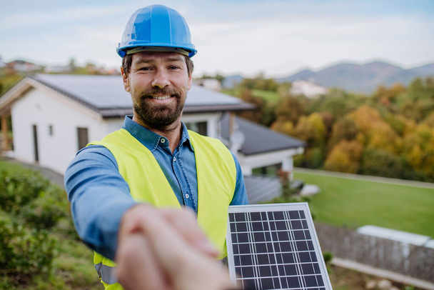 Smiling handyman, photovoltaics panels installer shaking hand with owner of the house. - Φωτογραφία, εικόνα
