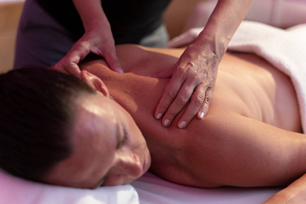 Une femme physiothérapeute faisant un massage avec une autre femme dans son dos - Photo, image