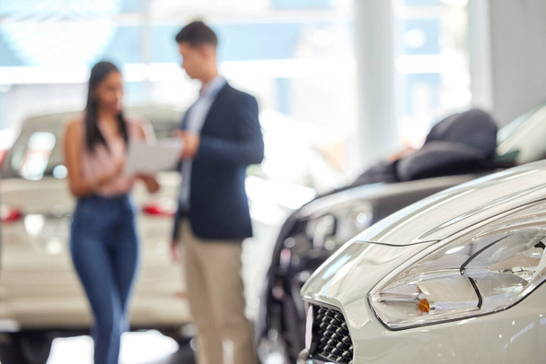Isnt time for a new car. a salesman assisting a young woman on the showroom floor - Φωτογραφία, εικόνα
