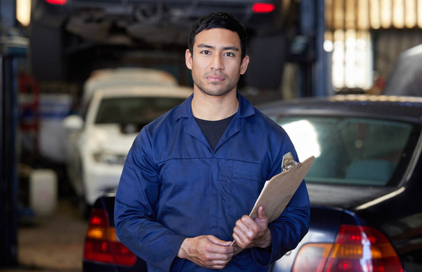 Lets get this inspections underway. Cropped portrait of a handsome young male mechanic holding a clipboard while standing in his workshop - Fotografie, Obrázek